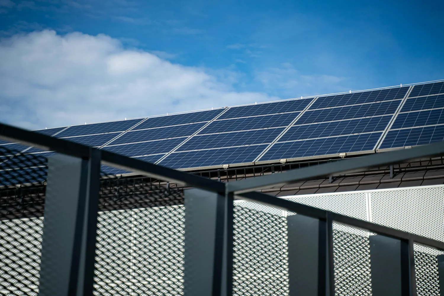 FK Systems GmbH - Technologie solaire - Des ouvriers installent des panneaux photovoltaïques sur le toit d'un bâtiment. Emplois dans le secteur des énergies renouvelables.